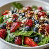 Vibrant Spinach and Berry Salad Bowl featuring strawberries, blueberries, and creamy goat cheese, ready to serve as a refreshing light lunch.