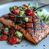 Flaky grilled salmon crowned with colorful strawberry avocado salsa, an irresistible seafood delight.