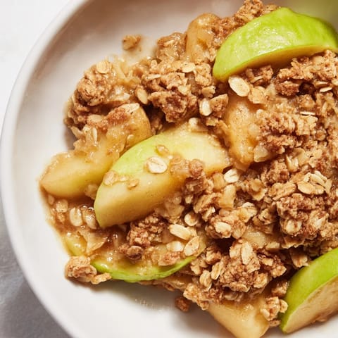 Golden-brown Apple Crumble, bubbling with sweet spiced apples, ready for a scoop of vanilla ice cream.