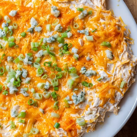 Golden, bubbly Buffalo Chicken Dip, served warm with crisp celery and tortilla chips for dipping.