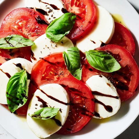 Close-up of a Caprese Salad with bright, juicy tomatoes and fragrant basil leaves in a layered arrangement.