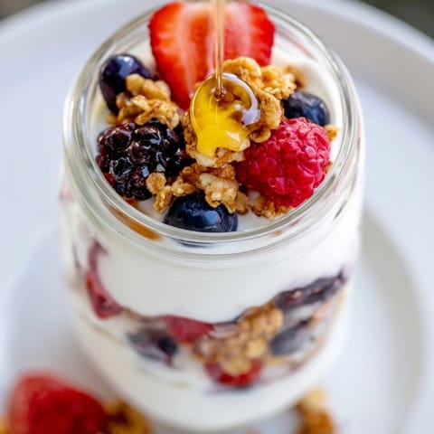 A vibrant berry parfait layered with creamy yogurt, crunchy granola, and fresh, juicy berries.