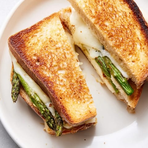 Golden-brown sourdough slices, filled with melted Brie and charred asparagus spears, create a warm, savory Asparagus & Brie Grilled Cheese sandwich.