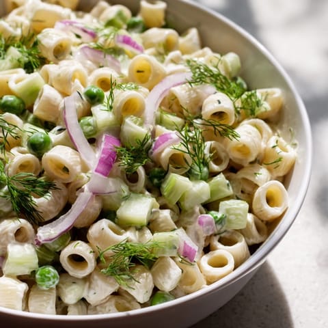 Overhead view of Creamy Dill Pickle Pasta Salad, garnished with fresh dill, ready for a spring potluck.