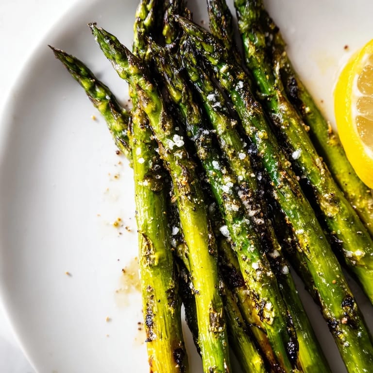 Golden-brown grilled asparagus, a vibrant vegan side dish, ready to serve with lemon wedges.
