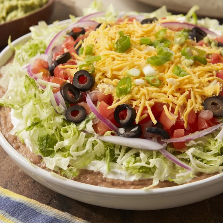A layered Tex-Mex party classic: Seven-Layer Dip showcasing creamy, colorful toppings and flavors.
