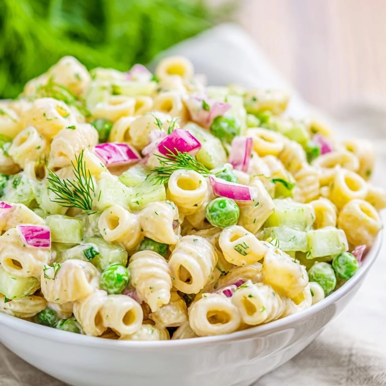 Close-up on Creamy Dill Pickle Pasta Salad showing creamy dressing coating ditalini, celery, red onion, and pickles.