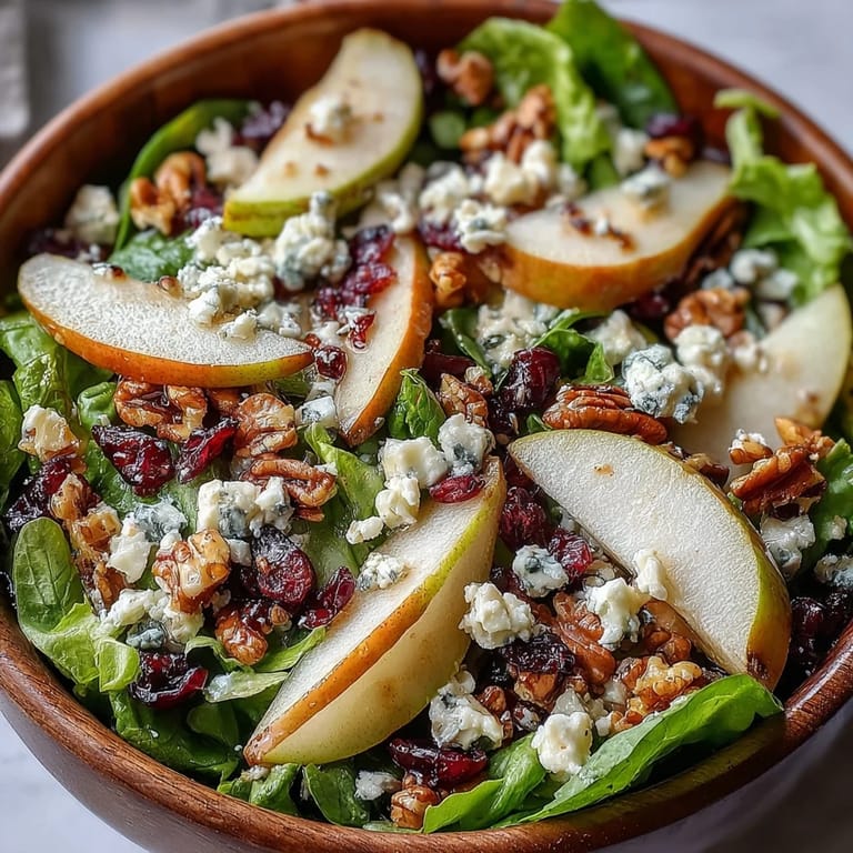 Savory mixed greens and crumbled Gorgonzola cheese share the plate with sweet pear slices, crunchy walnuts, and a glossy honey-balsamic vinaigrette.