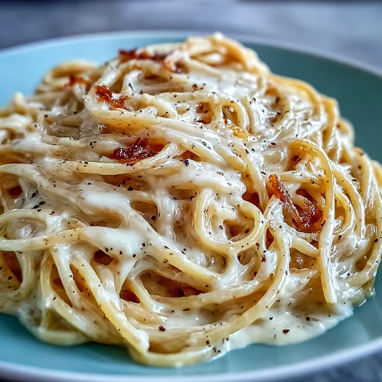 Close-up of creamy Cacio e Pepe showcasing al dente spaghetti and freshly cracked black pepper seasoning.