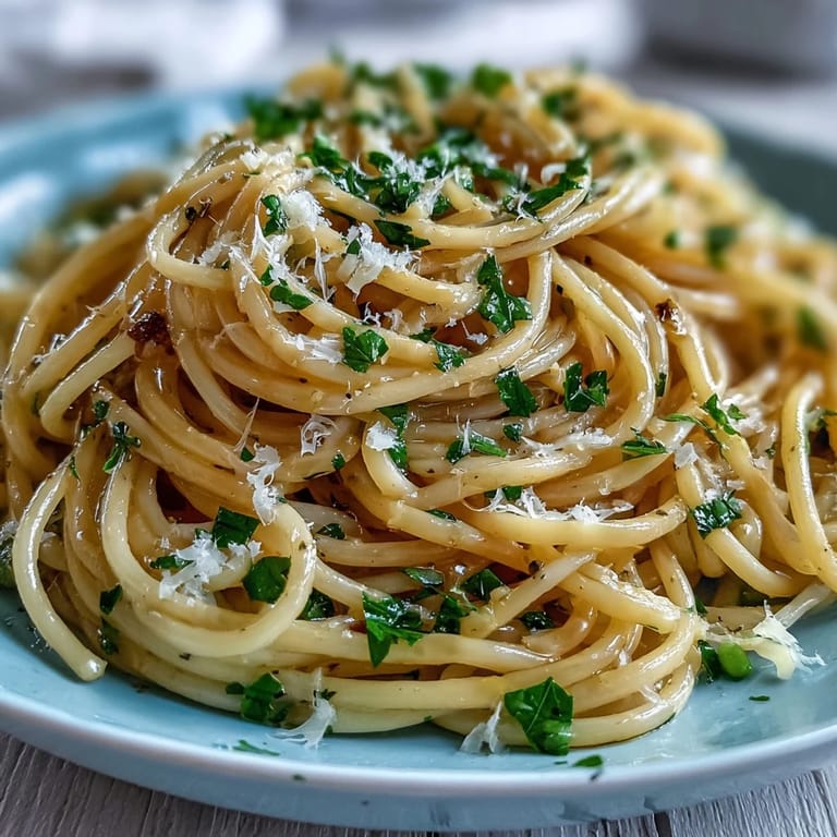 Close-up of al dente linguine tossed with lemon butter, green peas, and Parmesan, topped with a sprinkle of black pepper.