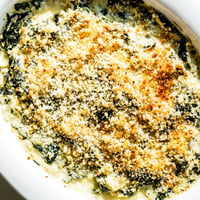 Golden brown Spinach Artichoke Dip, bubbling from the oven, ready to scoop with crackers.